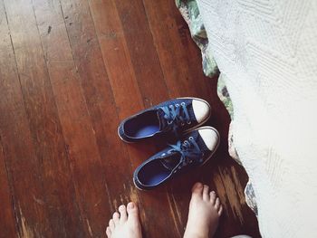 Low section of woman by shoes on hardwood floor