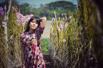 Portrait of woman standing amidst plants on field