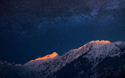 Scenic view of snowcapped mountains against sky at night