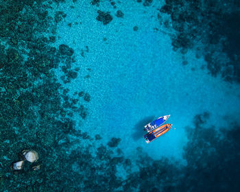 Amazing aerial image of blue and orange boats on still, crystal clear water.