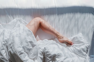Low section of woman lying on bed at home