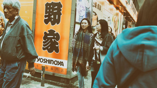 People standing by text on wall in city