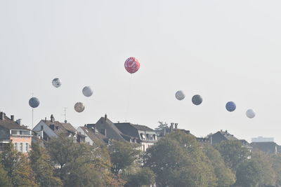 Hot air balloons flying over buildings against sky