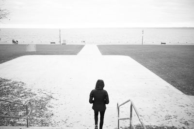 Rear view of woman climbing down stairs near a lake