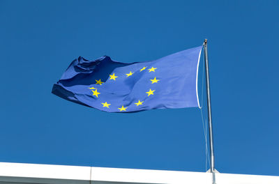 Low angle view of flag against blue sky