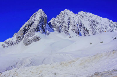 Scenic view of snowcapped mountains against blue sky