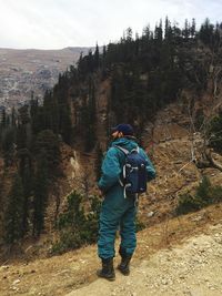 Rear view of man with umbrella on snow against trees