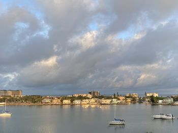 Sailboats in city by sea against sky