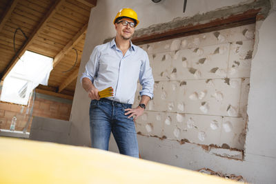 Man wearing hat standing against wall