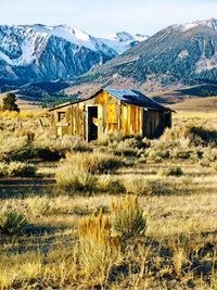 Abandoned house on field by mountain against sky