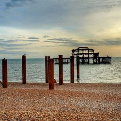 Pier on sea against cloudy sky