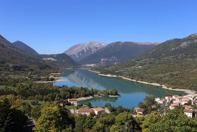 Scenic view of lake and mountains against clear blue sky