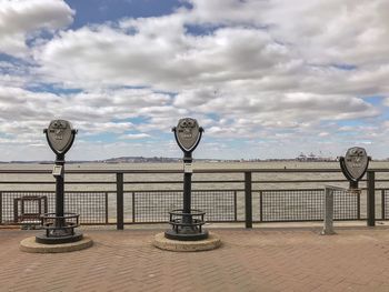 Street lights on railing by sea against sky