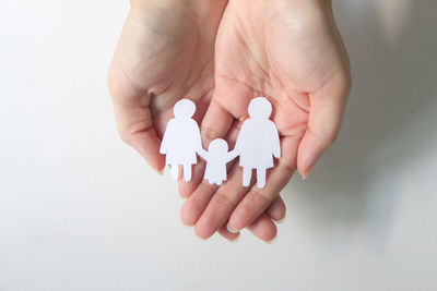 Cropped hand of person holding pills against white background