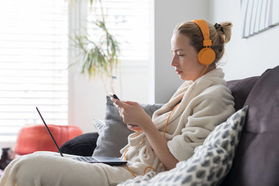 Side view of man using mobile phone while sitting on sofa