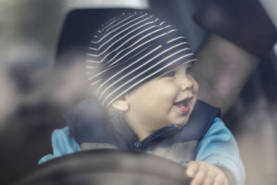 Cute smiling baby boy holding steering wheel while sitting in car