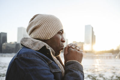 Man wearing knit hat warming hands in winter