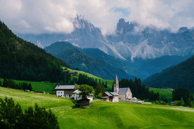 Houses on field by mountains against sky