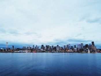 Sea by buildings against sky in city