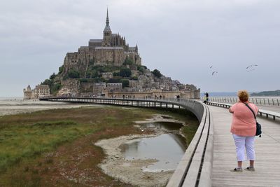 Rear view of woman standing on bridge against sky