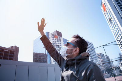 Low angle view of man standing by buildings against clear sky