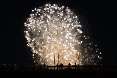 Low angle view of silhouette people against firework display at night