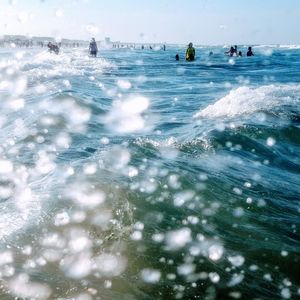 People swimming in sea against sky