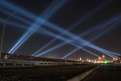 Train on illuminated railroad tracks against sky at night