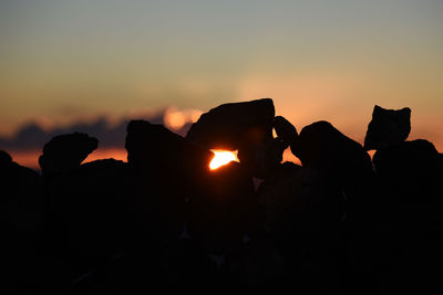 Silhouette rocks against sky during sunset