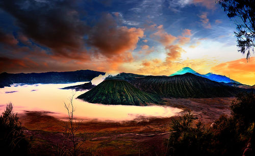 Scenic view of landscape against cloudy sky during sunset