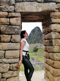 Young woman standing against ancient wall