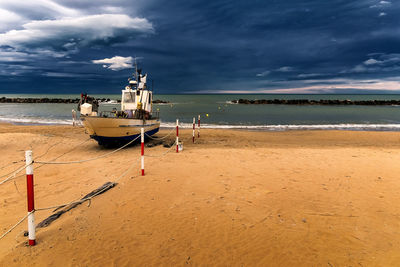 Boat moored on beach against sky