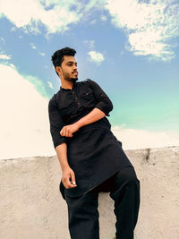 Young man looking away while standing on land against sky