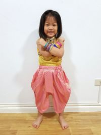 Portrait of smiling girl standing against wall at home