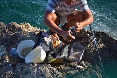 Low section of man holding rock in sea