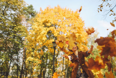 Happy woman throwing dry autumn leaves