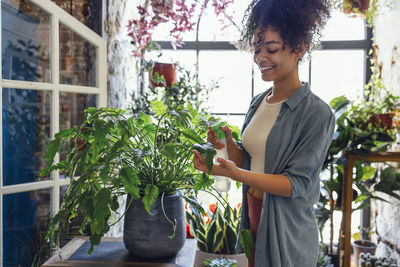 Portrait of young woman standing against plants