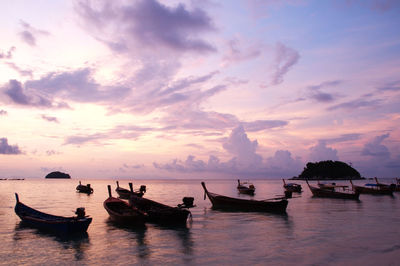 Fishing boats at sea against sky during sunset 