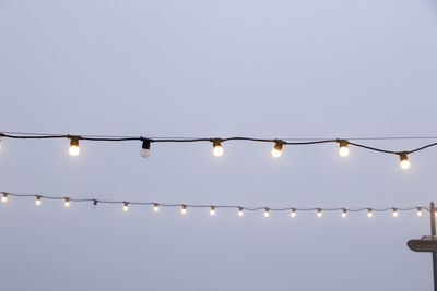 Low angle view of illuminated light bulbs against sky