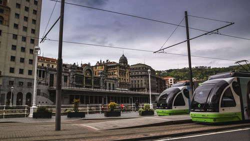 Cars on road by buildings against sky in city