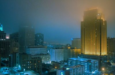 Illuminated cityscape against sky at night