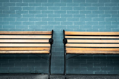 Empty two wooden bench on green brick wall background. waiting for someone to full fill empty bench.
