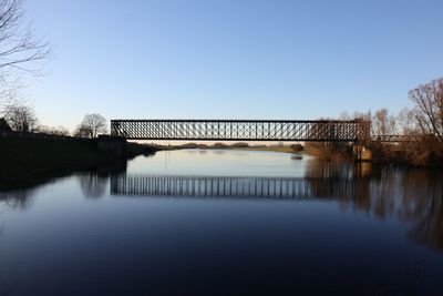 Bridge over lake against clear blue sky