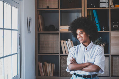 Smiling businesswoman looking through window at office