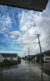 Road by buildings against sky in city