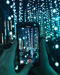 Man photographing illuminated city through smart phone