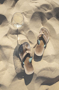 Wine glass and flip-flops on sandy beach