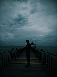 Man standing on pier over sea against sky