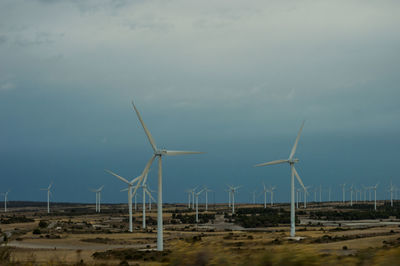 Wind turbines on land against sky