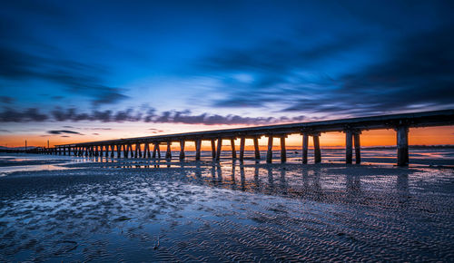 Bridge over sea against sky during sunset